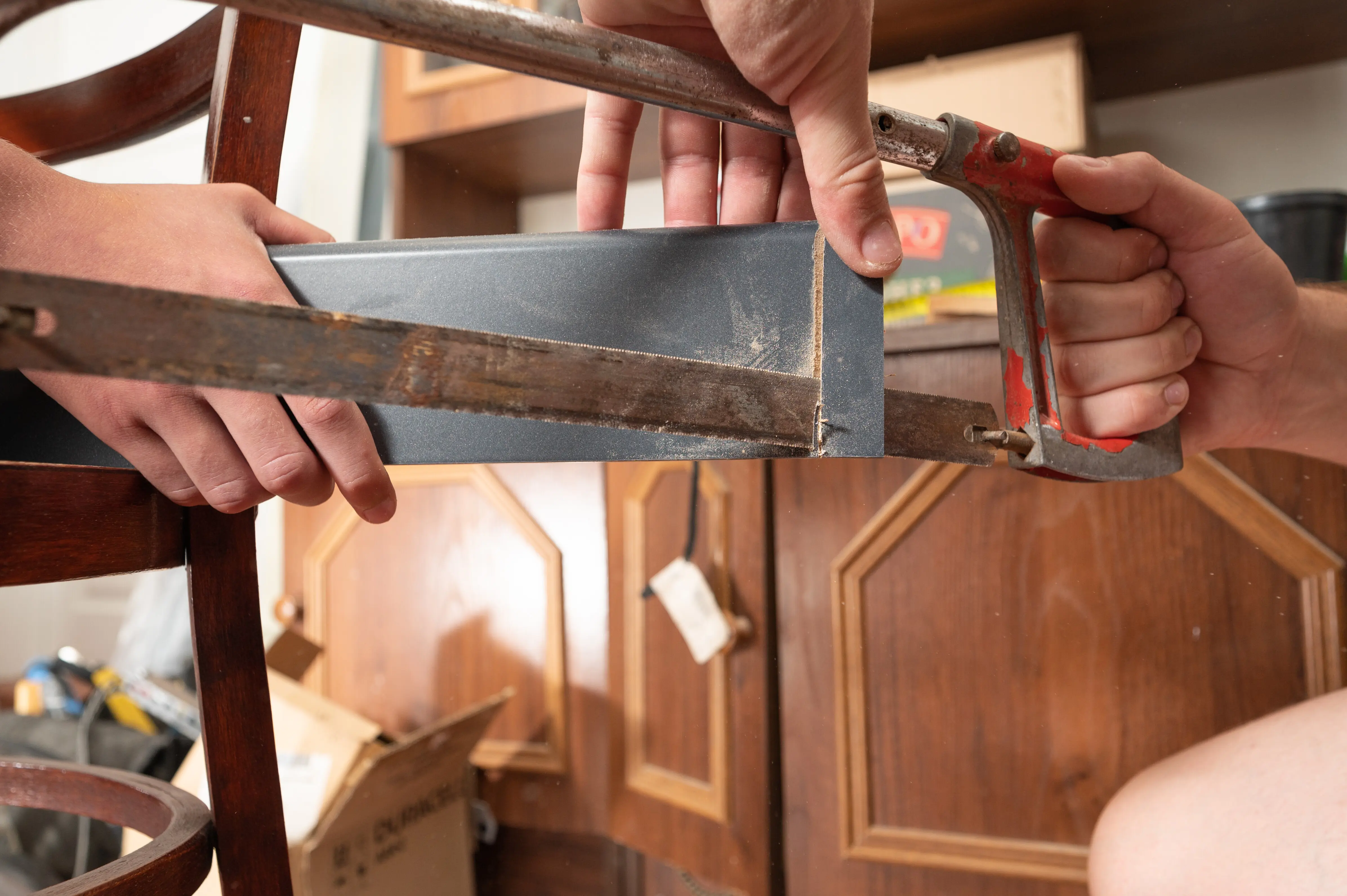 Kürzen eines hölzernen Sockels mit einer manuellen Stichsäge.