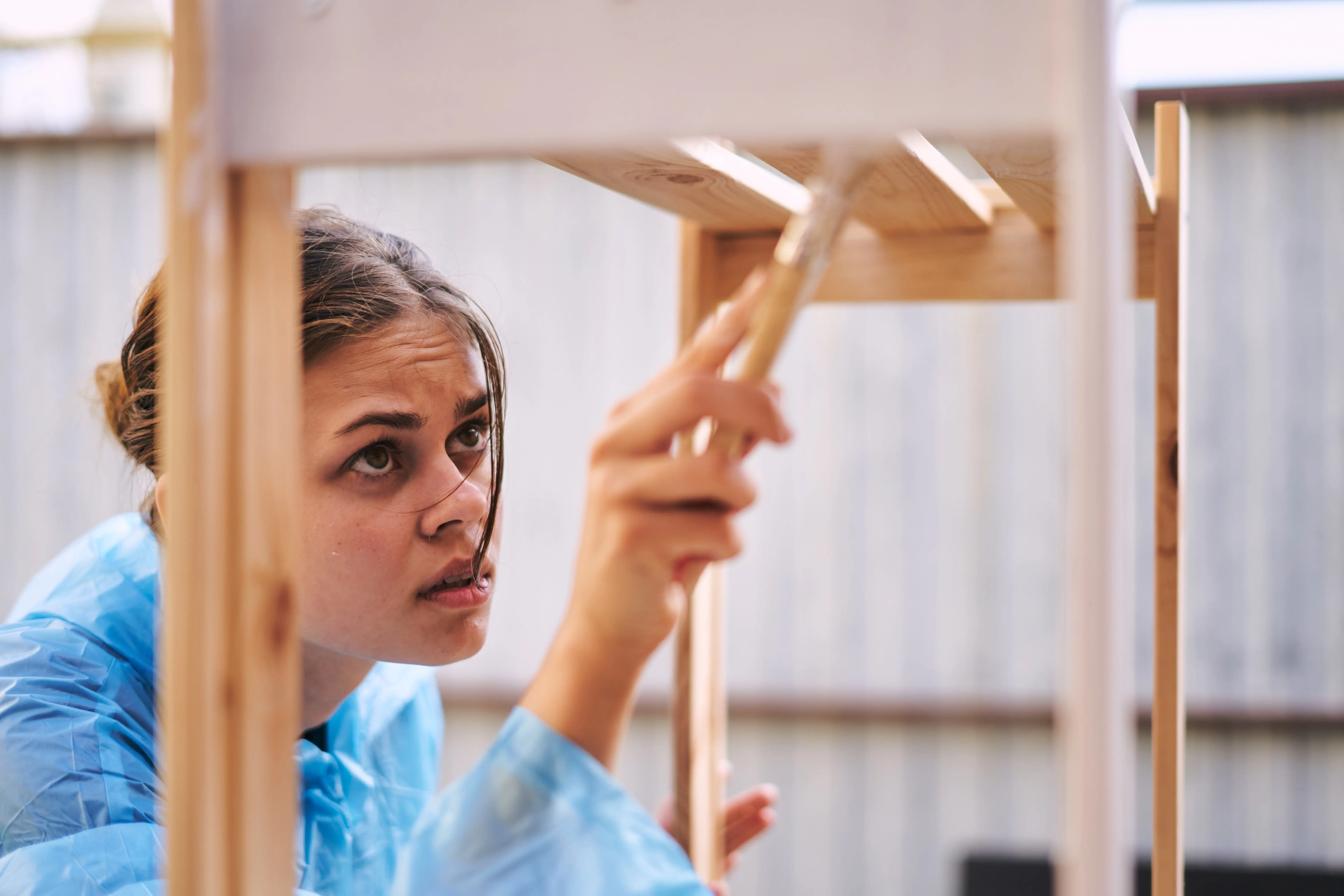 Porträt einer lächelnden jungen Frau, die an einer Wand steht.